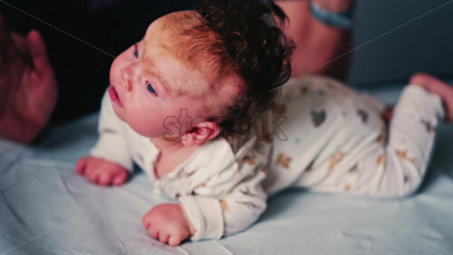 Video - Infant practicing tummy time on a padded surface while a caregiver gently supports the baby's back