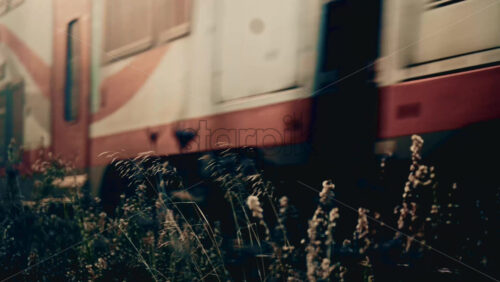 Video - Side view of a passenger train moving along railway tracks through an urban environment, with industrial textures and city elements visible in the background