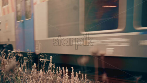 Video - Side view of a passenger train moving along railway tracks through an urban environment, with industrial textures and city elements visible in the background