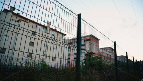 Video - Passenger train passing through, framed by overhead electric cables and surrounding buildings