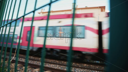 Video - Passenger train passing through, framed by overhead electric cables and surrounding buildings