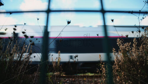 Video - Passenger train passing through, framed by overhead electric cables and surrounding buildings