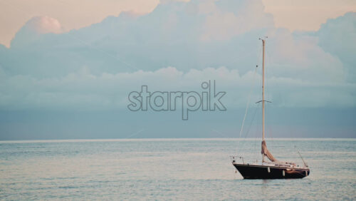 Video - Single sailboat moving steadily across calm water under a clear sky
