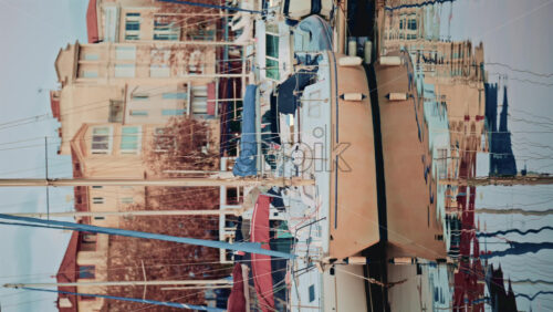 Video - Sailboats and yachts docked in a calm marina, reflected in still water with pastel colored residential buildings in the background. Vertical