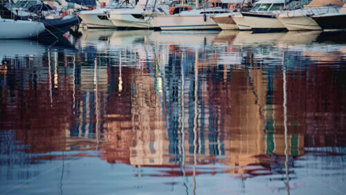 Video - Detailed shot of distorted reflections of buildings and boats on gently moving harbor water