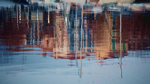 Video - Detailed shot of distorted reflections of buildings and boats on gently moving harbor water