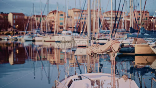 Video - View from the deck of a sailboat moored in a marina on the French Riviera, with masts and waterfront buildings reflected in still water