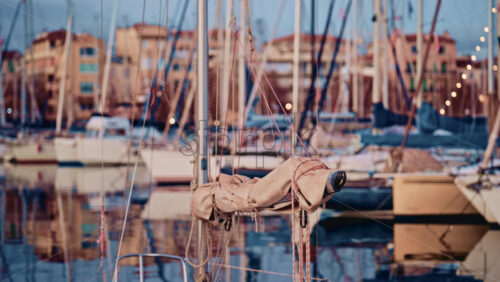 Video - View from the deck of a sailboat moored in a marina on the French Riviera, with masts and waterfront buildings reflected in still water