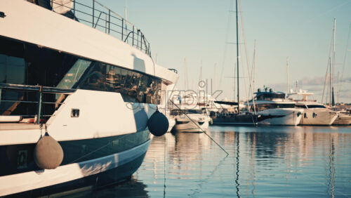Video - Luxury yachts docked at a marina with calm water reflections during golden hour