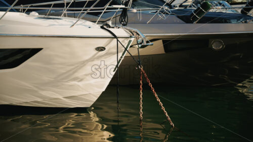 Video - Row of modern motor yachts tied at a marina, with calm water reflections and clear daylight