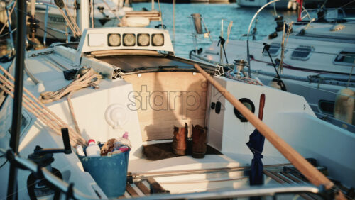 Video - Detailed view of a sailboat cockpit showing ropes, boots, and everyday sailing equipment illuminated by warm afternoon light