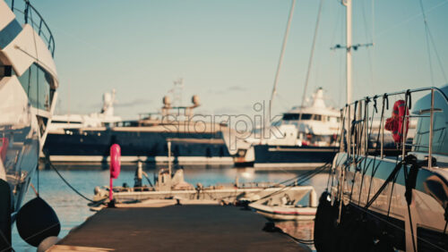 Video - View from a marina pier with yachts moored on both sides under clear daylight