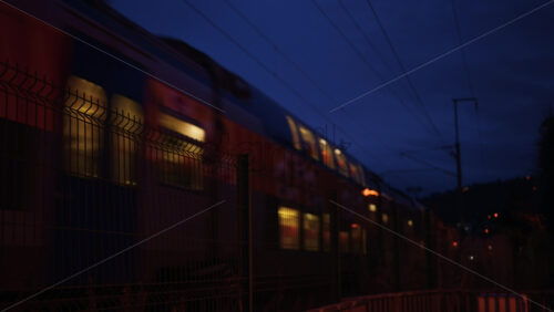 Video - Evening train moving through a fenced railway line in a quiet urban neighborhood