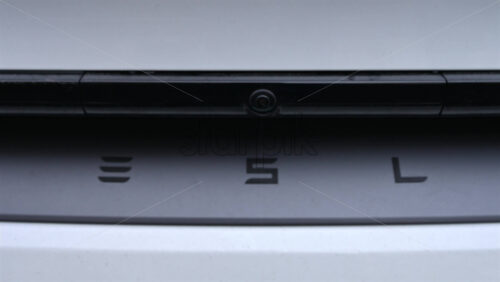 Video - Cannes, France - December 23, 2025: Close up of the Tesla logo on the rear of a white electric vehicle, with clean lines and modern automotive design
