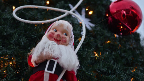 Video - Festive Santa Claus decoration displayed outdoors, framed by Christmas tree branches and warm holiday lights