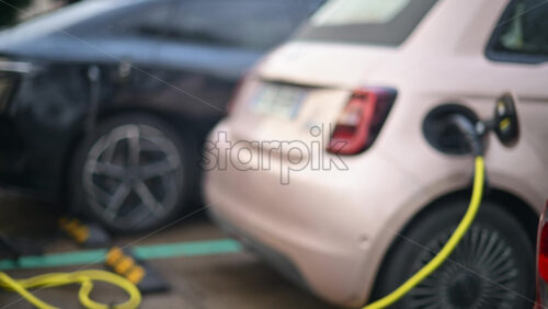 Video - Electric car connected to a public charging station in an outdoor parking area