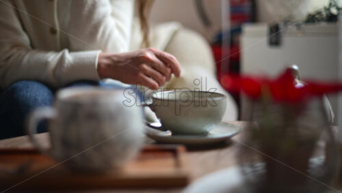 Video - Ceramic mug placed on a wooden tray with a red poinsettia plant in the foreground and a person softly blurred in the background