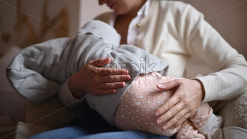 Video - Smiling mom gently holding a baby inside a cafe