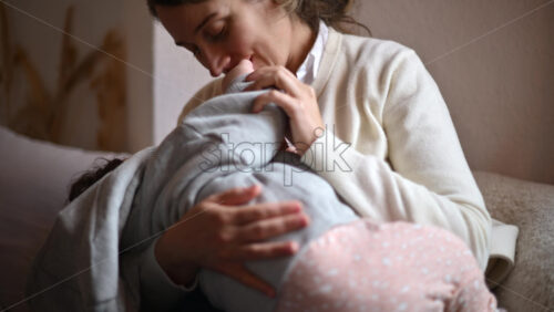 Video - Smiling mom gently holding and playing with a baby inside a cafe