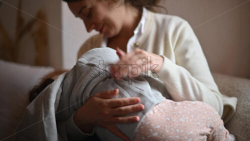 Video - Smiling mom gently holding and playing with a baby inside a cafe