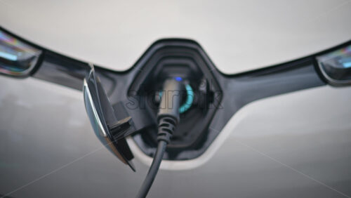 Video - Close up view of an electric vehicle charging cable connected to a white car