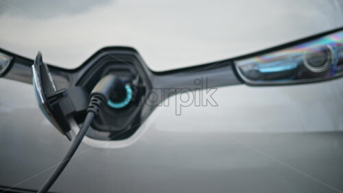 Video - Close up view of an electric vehicle charging cable connected to a white car