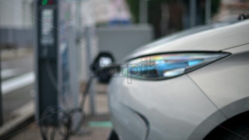 Video - White, electric vehicle parked at a public charging station in an urban environment