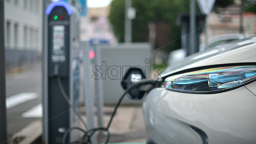Video - White, electric vehicle parked at a public charging station in an urban environment