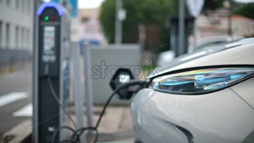 Video - White, electric vehicle parked at a public charging station in an urban environment