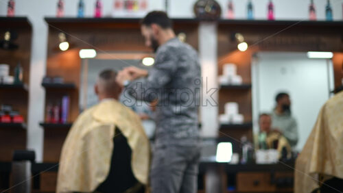 Video - Blurred view of a barber cutting a client's hair inside a modern barbershop