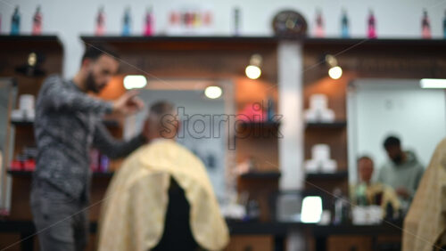 Video - Blurred view of a barber cutting a client's hair inside a modern barbershop