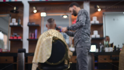 Video - Blurred view of a barber cutting a client's hair inside a modern barbershop