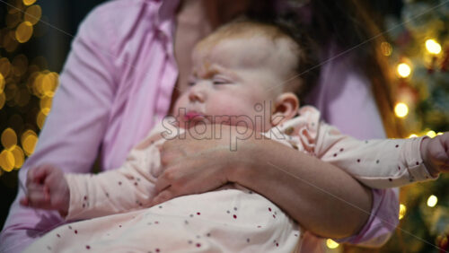 Video - Close up portrait of a baby held by her mother during the Christmas season