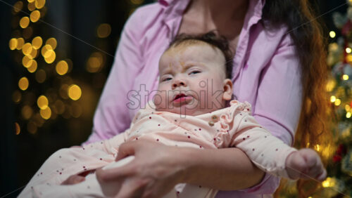 Video - Close up portrait of a baby held by her mother during the Christmas season