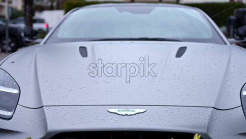 Video - Cannes, France - December 23, 2025: Close up view of an Aston Martin logo on a luxury sports car with rain droplets on the surface