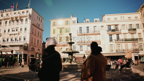 Video - Cannes, France - December 23, 2025: People sitting and relaxing around a water fountain in a lively square