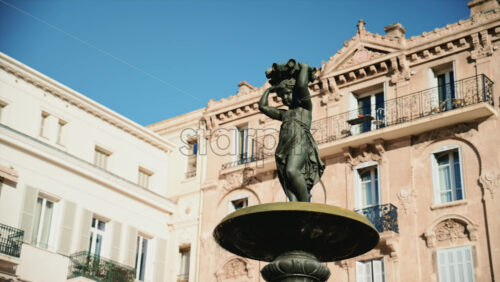 Video - Close up view of a bronze fountain statue with flowing water, surrounded by classic architecture in the Place du General de Gaulle