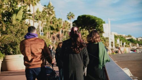 Video - Cannes, France - December 23, 2025: Pedestrians walking along La Croisette on a sunny day, with palm trees, benches, and the Mediterranean Sea in the background