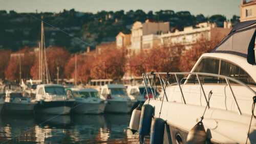 Video - Boats docked at a marina with hillside residential buildings and autumn trees in the background