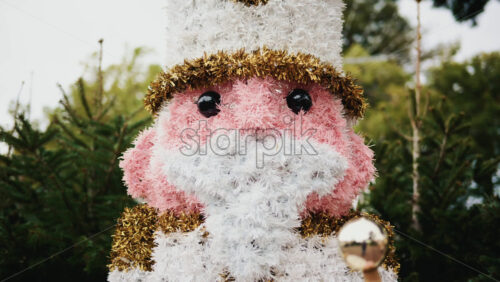 Video - Decorative Christmas nutcracker soldier figure displayed outdoors with trees in the background