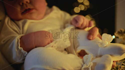 Video - Baby being held close to a decorated Christmas tree, reaching toward illuminated ornaments and lights