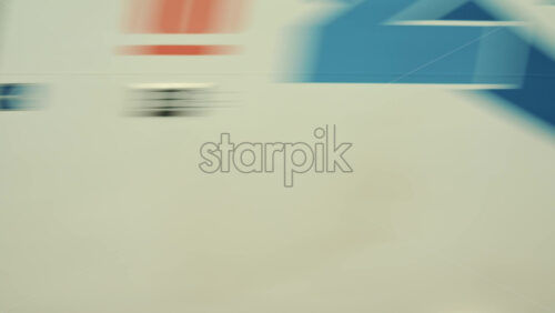 Video - Side view of a passenger train moving past a blue fence near the railway tracks