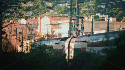 Video - Close up of an electric train passing beneath overhead power lines and utility structures