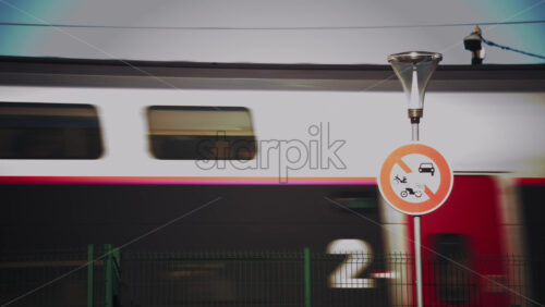 Video - Side view of a passenger train moving past a green fence near the railway tracks