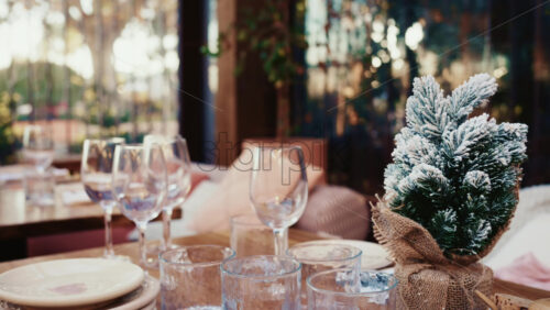 Video - Cozy table setting with glassware and a small snow covered Christmas tree decoration at a resturant