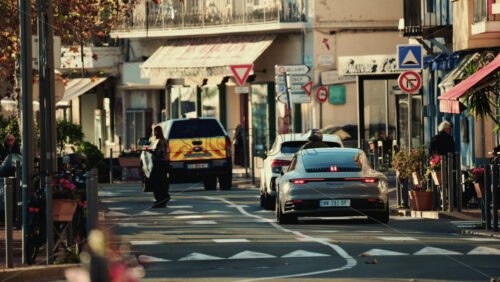 Video - Vallauris, France - December 27, 2025: Urban street scene with cars stopped on the road and a pedestrian crossing