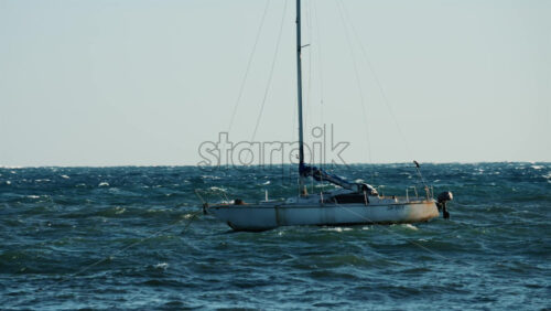 Video - Single sailboat floating on rough water with visible waves and wind movement