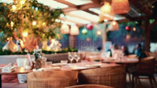Video - Wide shot of a restaurant interior with wooden tables, chairs, hanging lights, and decorative plants