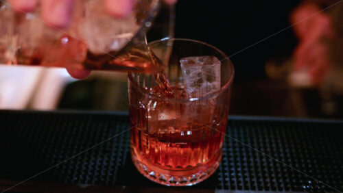 Video - Detailed close up of a cocktail being poured into a glass over ice