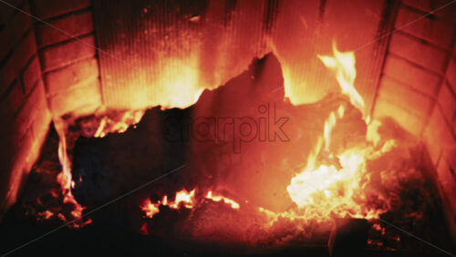 Video - Burning firewood inside a fireplace with glowing embers and warm flames
